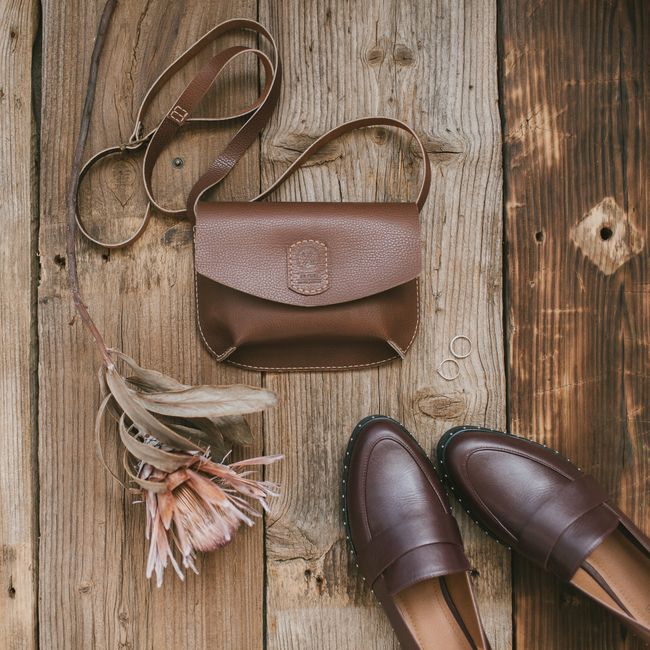Bolsa de couro e sapatos sobre mesa de madeira